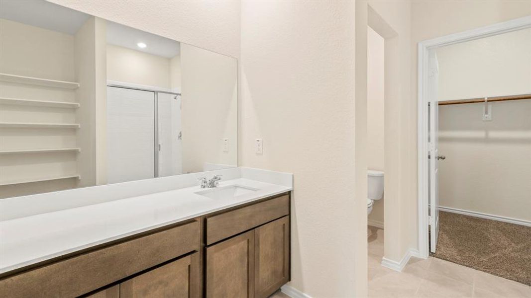 Double vanity with undermount sinks, white countertop, and wood-finish cabinetry