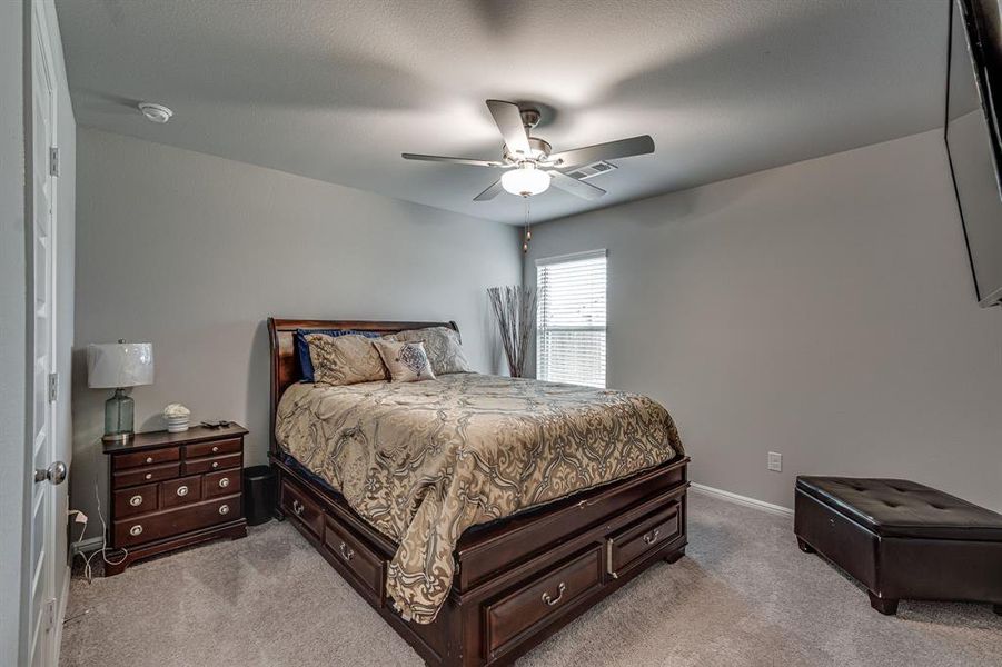 Bedroom with ceiling fan and light carpet