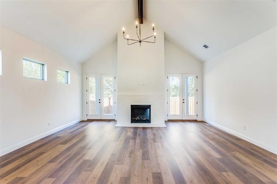 Unfurnished living room featuring french doors, dark hardwood / wood-style flooring, high vaulted ceiling, and a healthy amount of sunlight