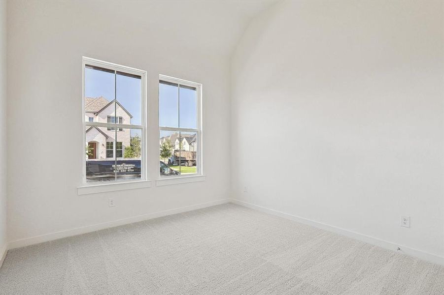 Carpeted empty room with lofted ceiling and a wealth of natural light