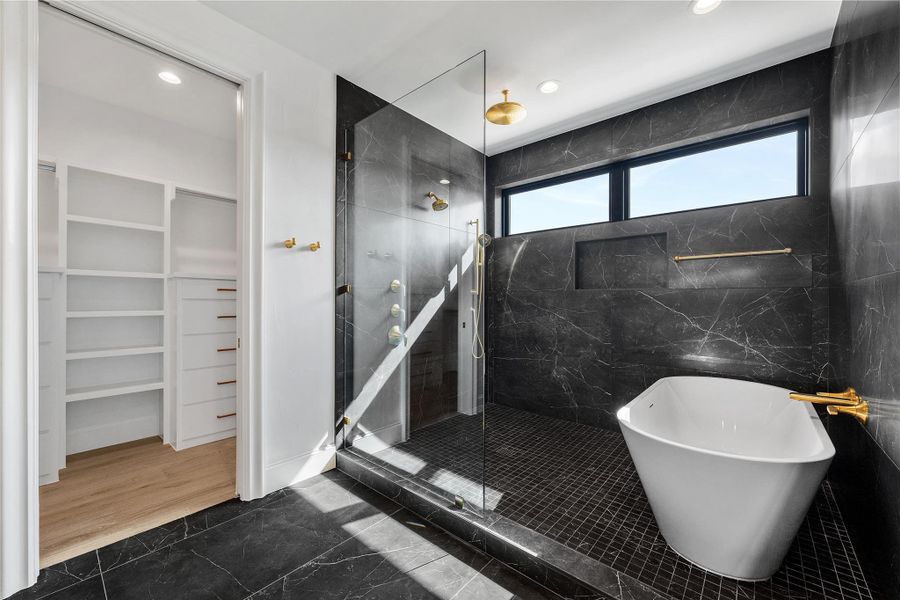 Full bath featuring tiled shower, a spacious closet, a freestanding tub, recessed lighting, and dark marble finish flooring