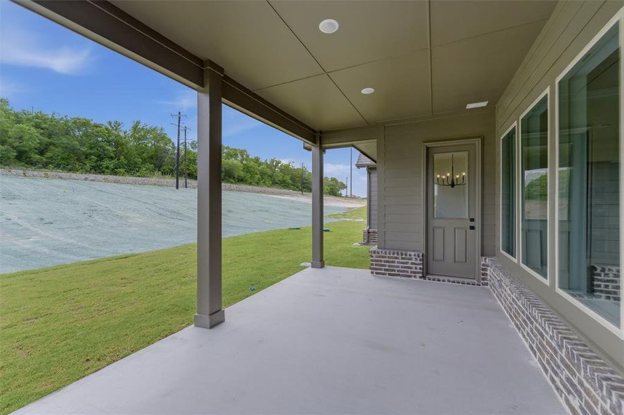 Covered patio with a smooth concrete surface, recessed lighting, and a painted wood-frame door with a glass insert