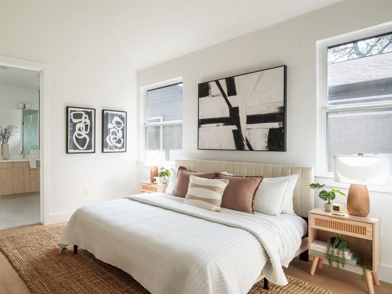 Bedroom featuring light wood-finish flooring and two windows with roller shades