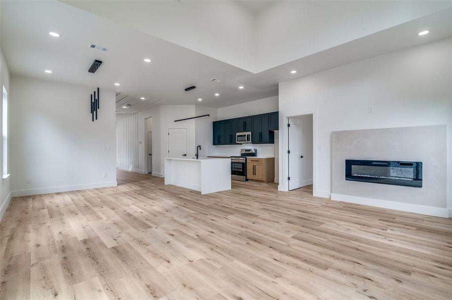 Unfurnished living room featuring recessed lighting, light wood finished floors, and a glass covered fireplace