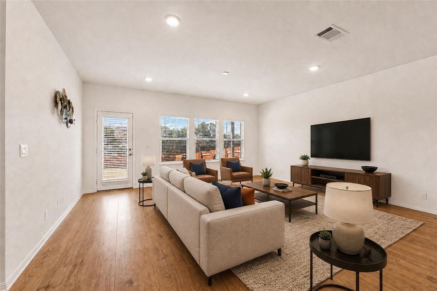 Living area showcasing recessed lighting, rich hardwood flooring and outdoor access.