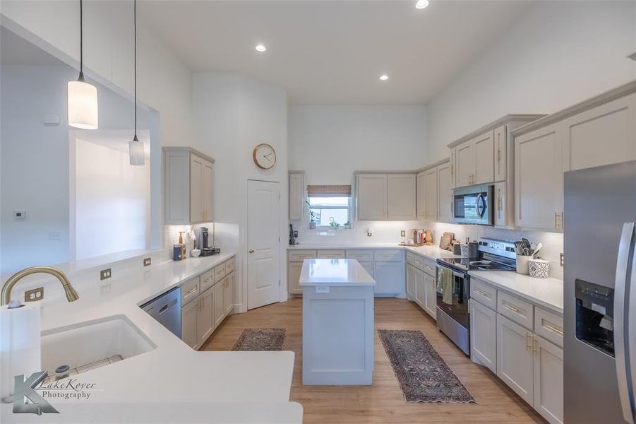Kitchen with appliances with stainless steel finishes, pendant lighting, light wood finished floors, tasteful backsplash, and recessed lighting Kitchen with appliances with stainless steel finishes, pendant lighting, light wood finished floors, tasteful backsplash, and recessed lighting