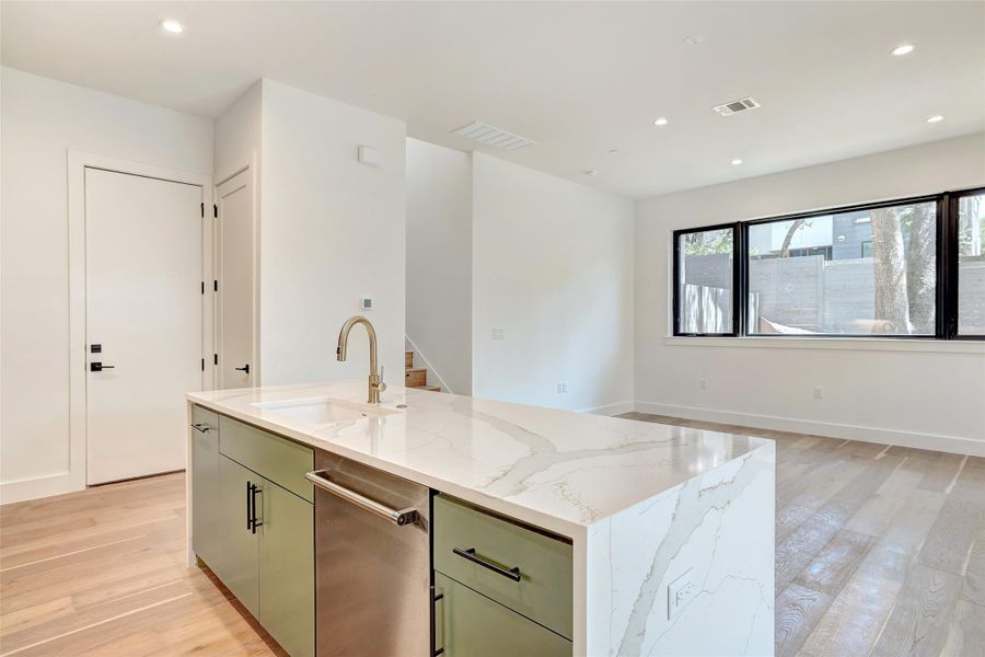 Kitchen with a sink, light wood finished floors, recessed lighting, light stone counters, and open floor plan