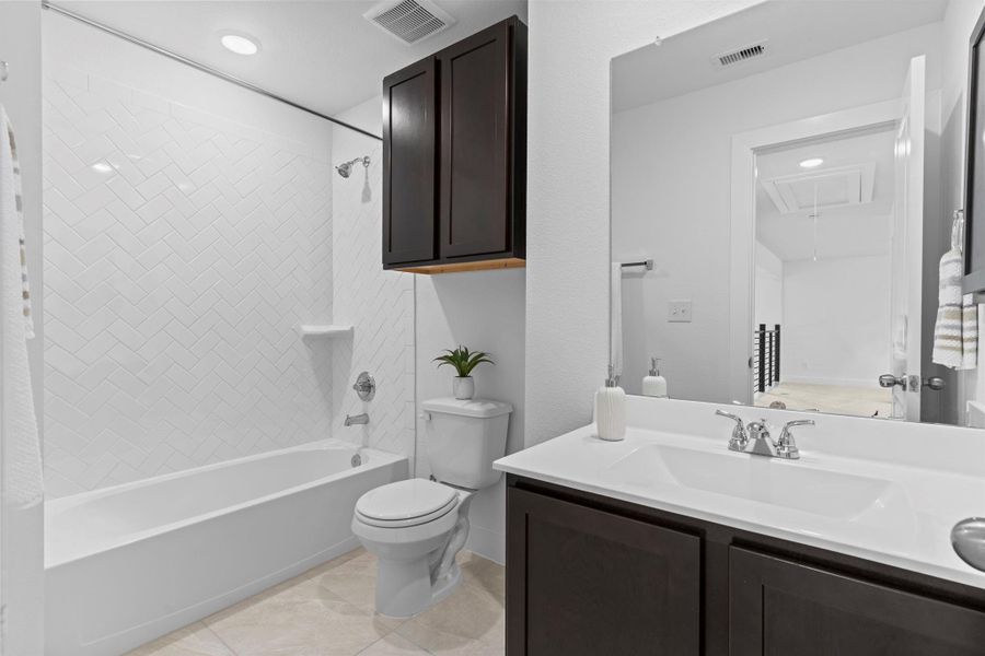Full upstairs bathroom features a tub/shower combo, dual-sink vanity with cultured marble countertops, and stylish dark cabinetry—perfect for shared use. **Image Representative of Plan Only and May Vary as Built**.