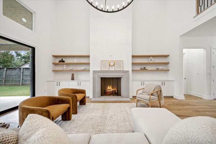 Living room featuring a high ceiling, hardwood flooring, and a notable chandelier