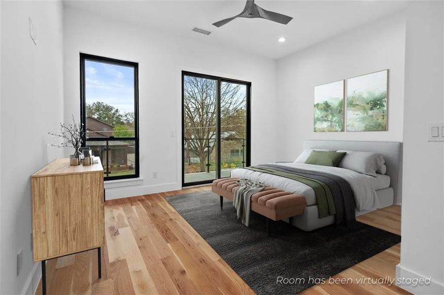 Bright room featuring wide plank wood-finish flooring, a modern ceiling fan, recessed lighting, and a full-height glass door opening to an exterior balcony Bright room featuring wide plank wood-finish flooring, a modern ceiling fan, recessed lighting, and a full-height glass door opening to an exterior balcony