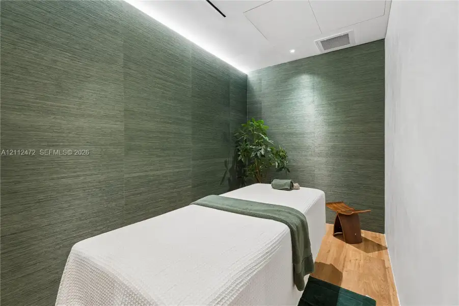 Textured forest-green wall panels, recessed ceiling lighting, and wood-finish flooring