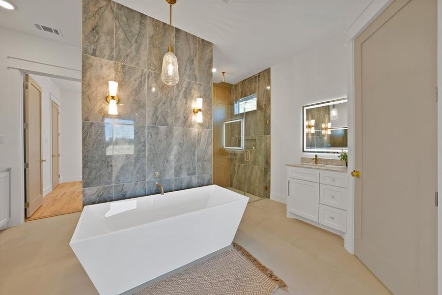 Full bathroom featuring a stall shower, a freestanding bath, tile walls, vanity, and recessed lighting
