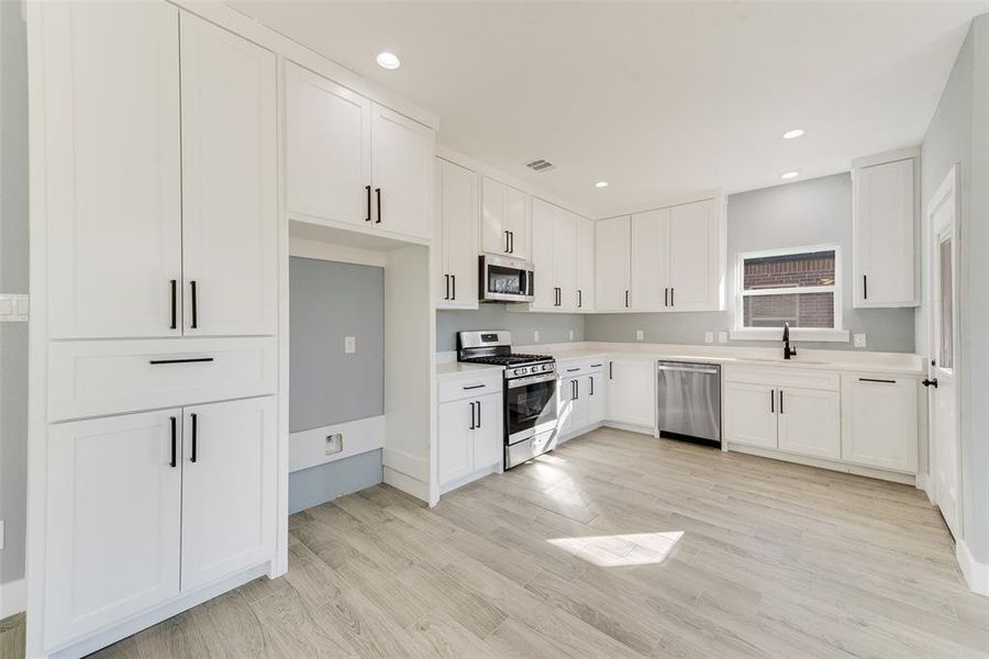 Kitchen featuring white cabinetry, appliances with stainless steel finishes, sink, and light hardwood / wood-style flooring