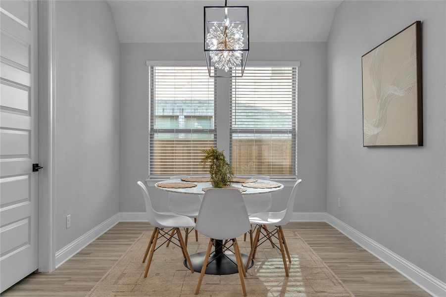 Dining room with light wood-style flooring, lofted ceiling, and a chandelier Dining room with light wood-style flooring, lofted ceiling, and a chandelier