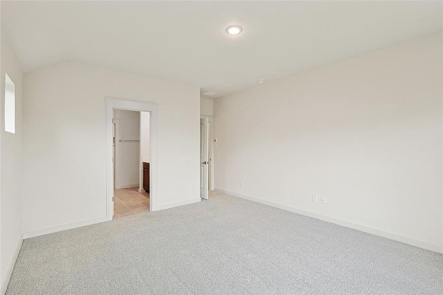 Unfurnished room featuring vaulted ceiling and light carpet