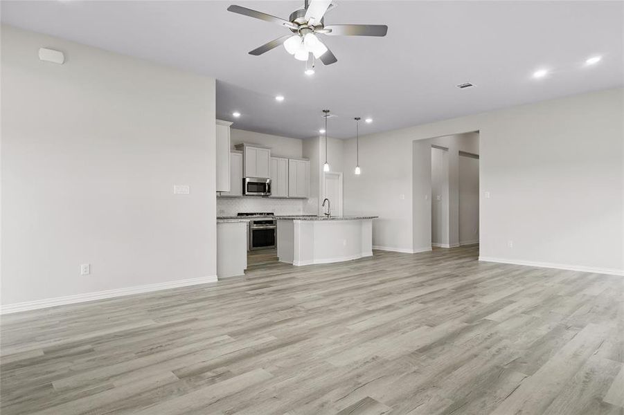 Unfurnished living room featuring light wood-type flooring, ceiling fan, baseboards, and recessed lighting Unfurnished living room featuring light wood-type flooring, ceiling fan, baseboards, and recessed lighting