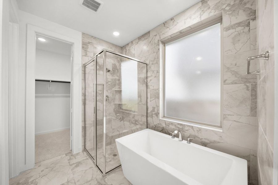 A luxurious primary bathroom showcasing a spacious shower, elegant freestanding tub, and a window that brings in natural light. A luxurious primary bathroom showcasing a spacious shower, elegant freestanding tub, and a window that brings in natural light.