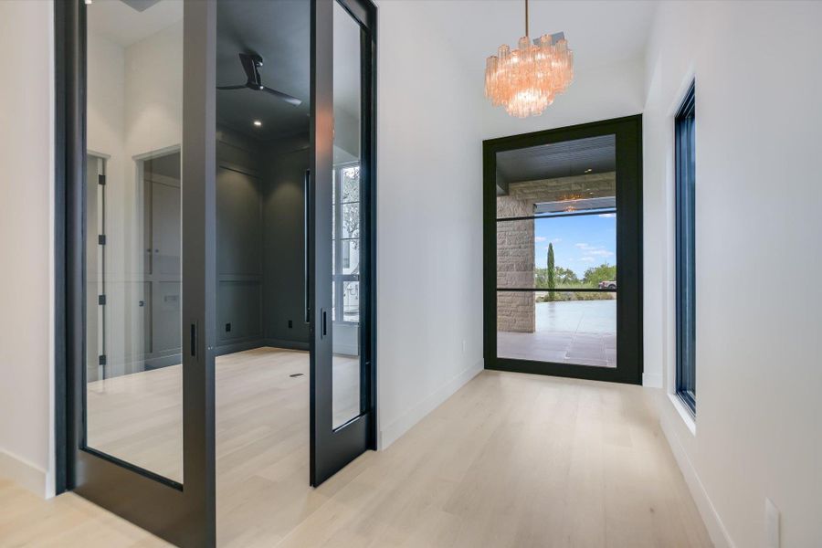 Blonde wood flooring extends through this airy entry, leading to an inviting office space and views of the patio.