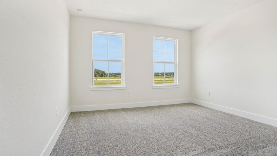 Bright bedroom with large windows in the Plumeria plan at Lakeside at Satilla by DRB Homes. Bright bedroom with large windows in the Plumeria plan at Lakeside at Satilla by DRB Homes.