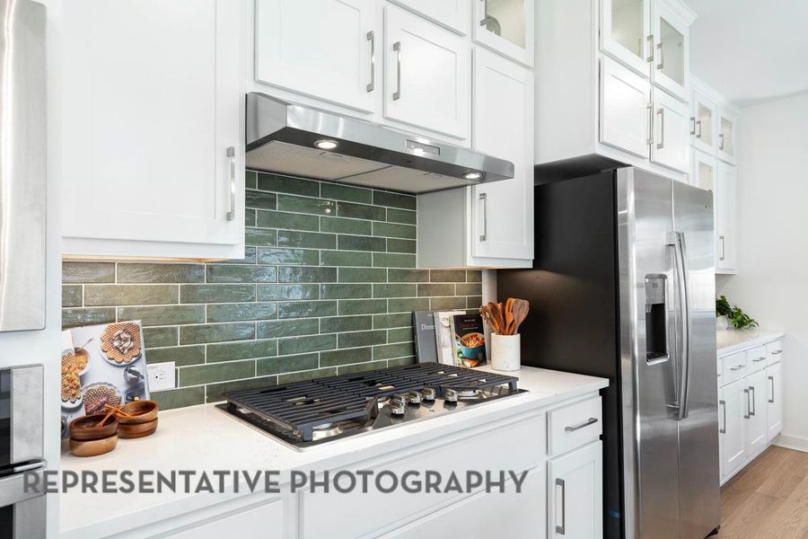 Kitchen featuring under cabinet range hood, appliances with stainless steel finishes, light countertops, and white cabinets Kitchen featuring under cabinet range hood, appliances with stainless steel finishes, light countertops, and white cabinets