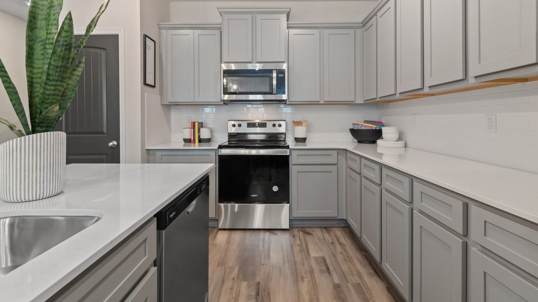 Kitchen with grey cabinetry, quartz countertops, and tile backsplash