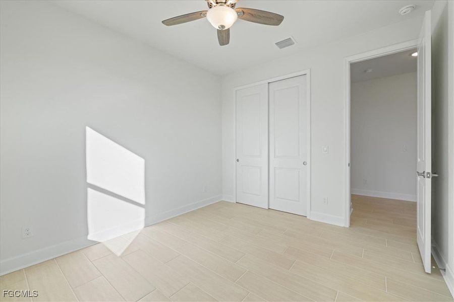 Unfurnished bedroom featuring ceiling fan, a closet, and wood tiled floors Unfurnished bedroom featuring ceiling fan, a closet, and wood tiled floors