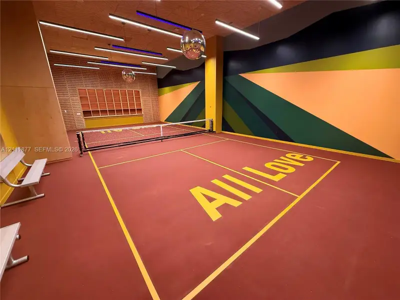 Indoor recreation court featuring high-contrast graphic wall treatments, linear LED lighting, natural wood-paneled walls, and built-in metal bench seating