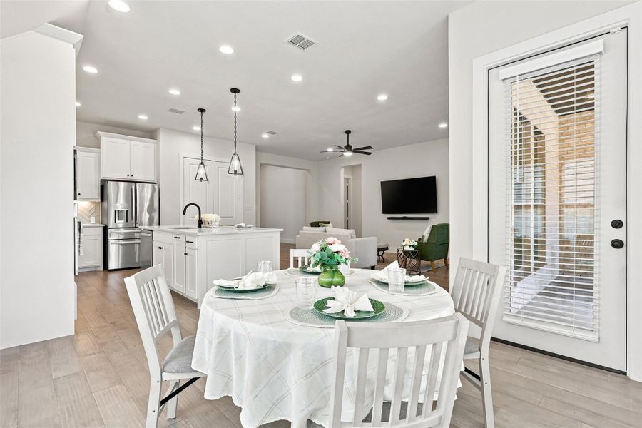 An open concept design seamlessly connects the dining area to a well-appointed kitchen and comfortable living space, featuring wood flooring and recessed lighting.