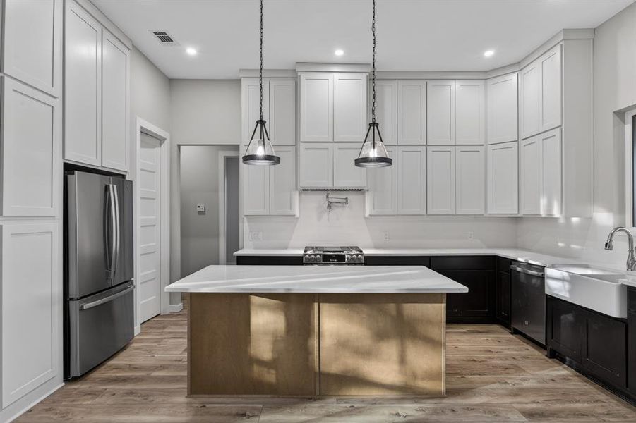 Kitchen features beautiful island, apron-front farmhouse sink, refrigerator, gas range and oven, dishwasher, pot filler and oversized pantry.