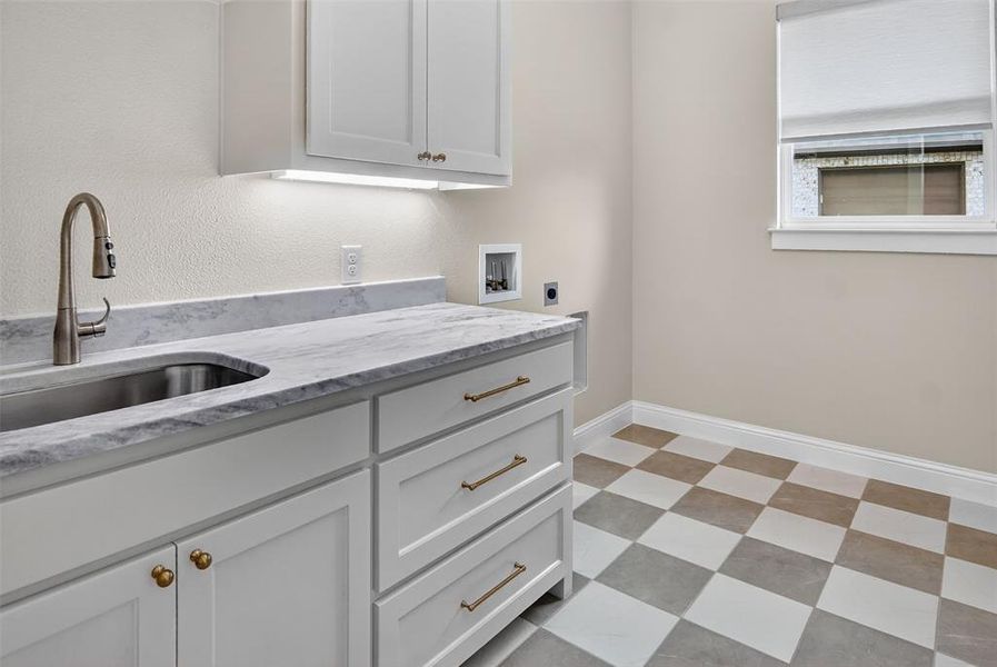 Washroom with hookup for a washing machine, cabinet space, electric dryer hookup, light flooring, and a textured wall