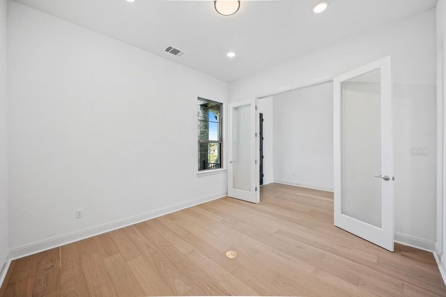 Home office featuring light wood-style floors, french doors, and recessed lighting