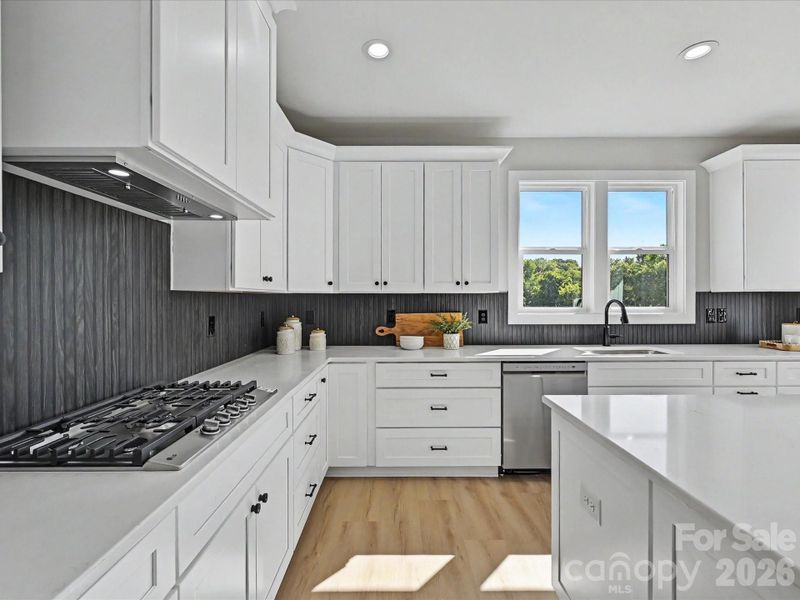 Designer kitchen and dining area showcase a massive quartz island, gas cooktop, stylish lighting, and sun-filled open layout ideal for entertaining and everyday living.