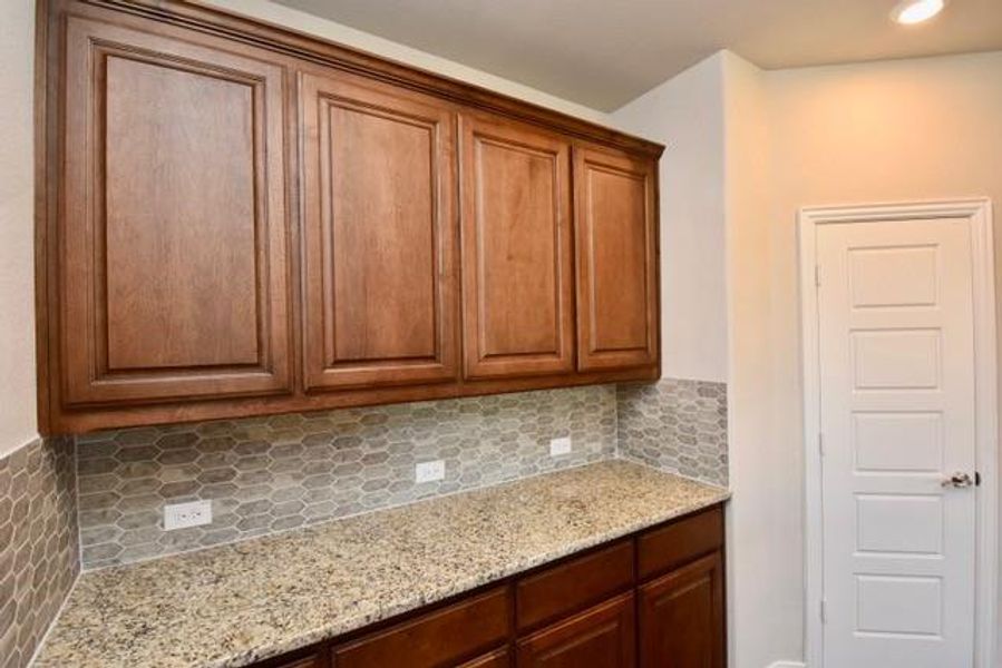 Kitchen featuring light stone countertops, brown cabinets, tasteful backsplash, and recessed lighting Kitchen featuring light stone countertops, brown cabinets, tasteful backsplash, and recessed lighting