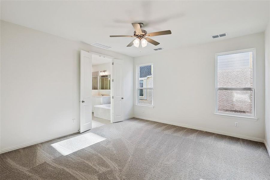 Unfurnished bedroom featuring ensuite bath, ceiling fan, and light colored carpet