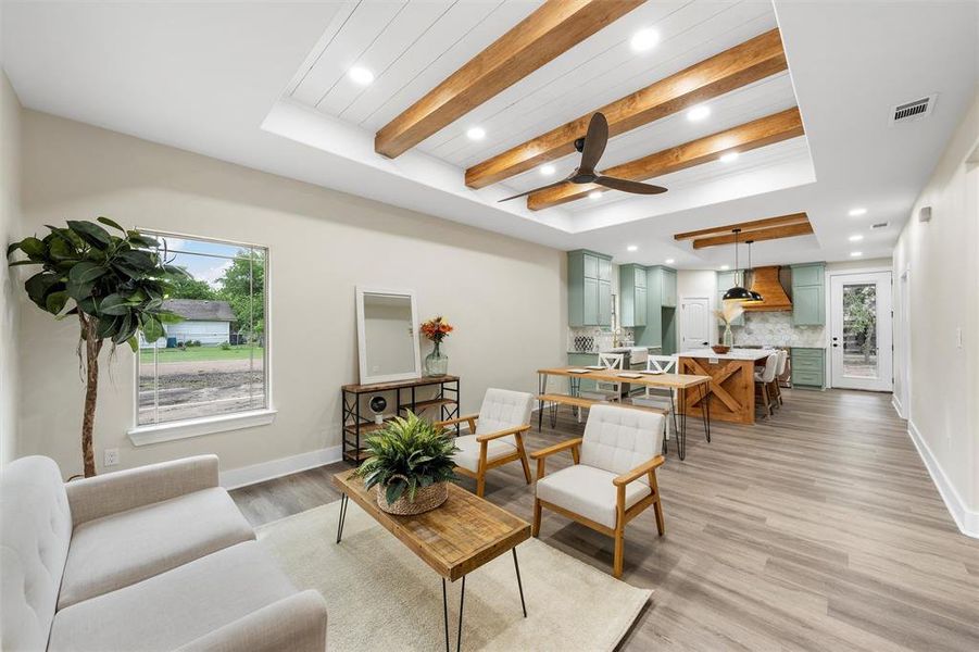 Living room featuring beam ceiling, light wood-type flooring, ceiling fan, recessed lighting, and baseboards