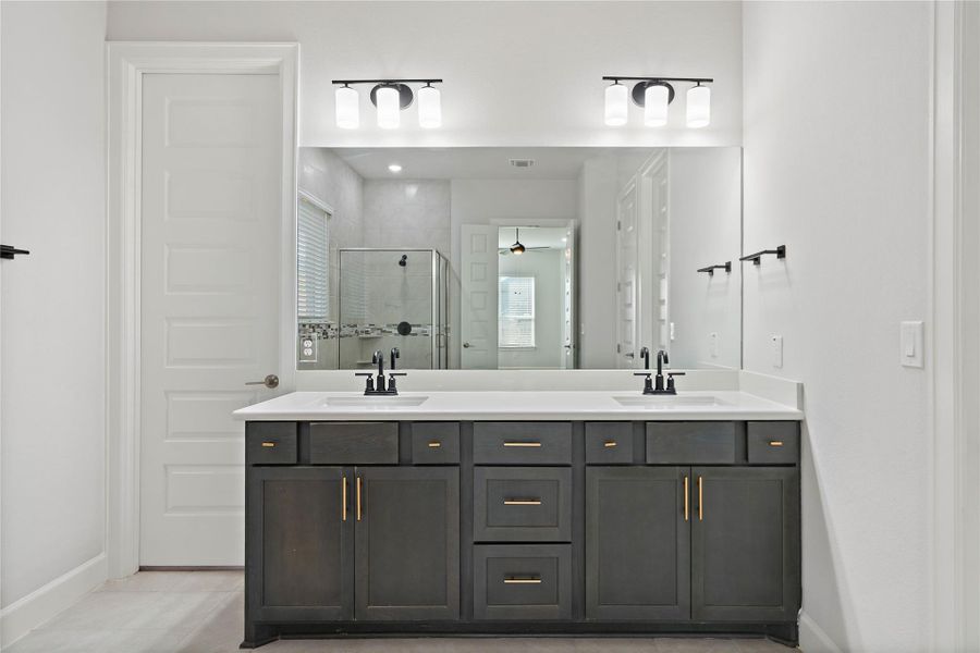 A spacious double vanity features sleek dark cabinetry paired with crisp white stone countertops.