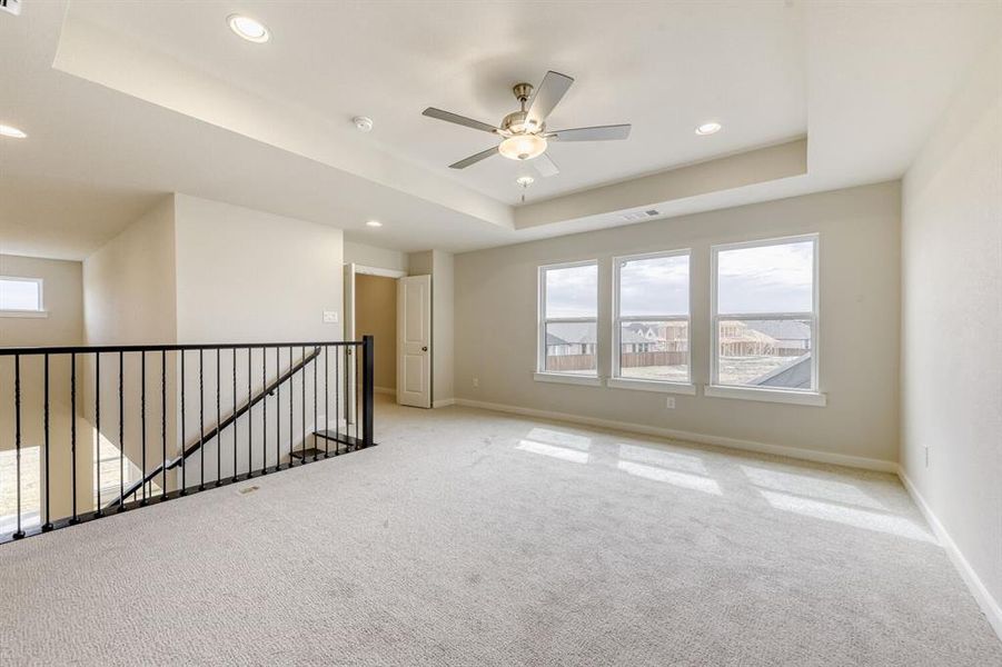 Carpeted empty room featuring a tray ceiling, ceiling fan, and recessed lighting