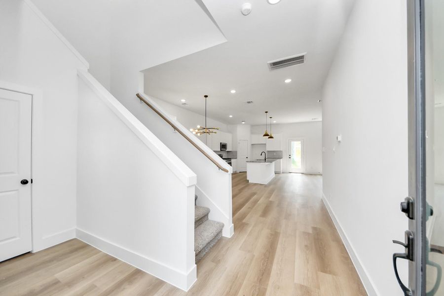 Entry & Living Area – Welcoming entry opens to a spacious open-concept living area with modern lighting, durable wood-look flooring, and a bright, airy feel.