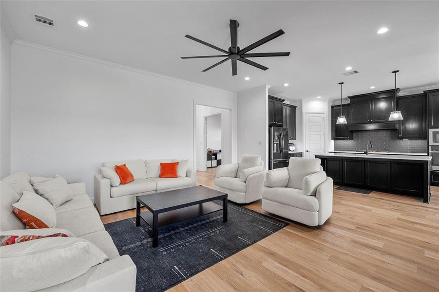 Living area with crown molding, light wood-type flooring, recessed lighting, and a ceiling fan Living area with crown molding, light wood-type flooring, recessed lighting, and a ceiling fan