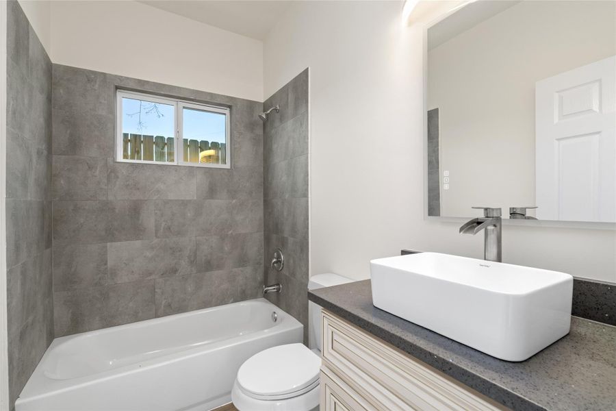 Full bathroom featuring tub/shower combo with elegant tile surround and modern vanity.