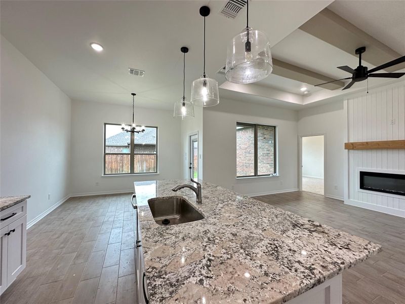 Kitchen island with a stainless steel sink and granite countertop, featuring three glass pendant lights