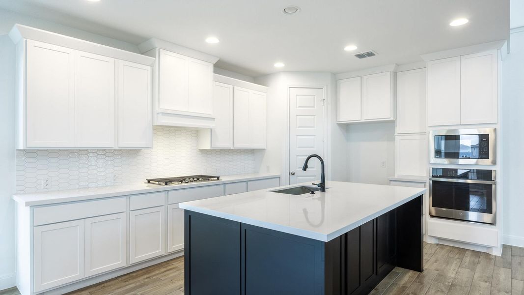 Kitchen with backsplash, light wood-style floors, stainless steel appliances, recessed lighting, and white cabinetry Kitchen with backsplash, light wood-style floors, stainless steel appliances, recessed lighting, and white cabinetry