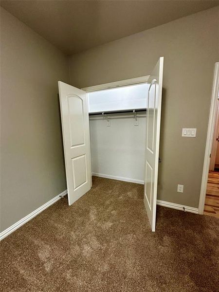 Unfurnished bedroom featuring dark carpet and a closet