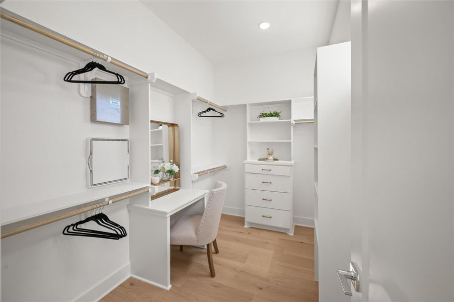 An oversized walk-in closet with built-in storage and a dedicated vanity area adds a boutique dressing room feel to the primary suite