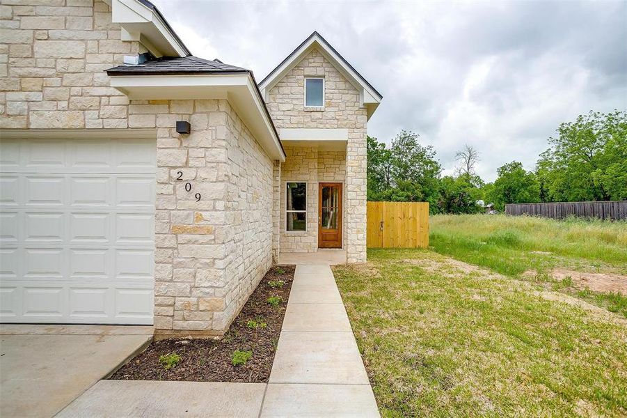 Doorway to property featuring fence and stone siding Doorway to property featuring fence and stone siding
