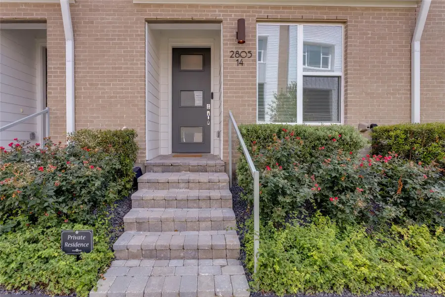 A welcoming stone walkway leads to the sleek front door of this modern brick townhome.