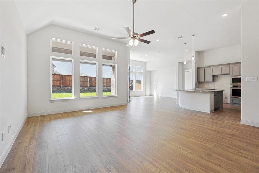 Unfurnished living room with a ceiling fan, a high ceiling, light wood-type flooring, and recessed lighting