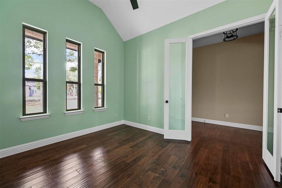 Empty room with french doors, lofted ceiling, and hardwood / wood-style floors