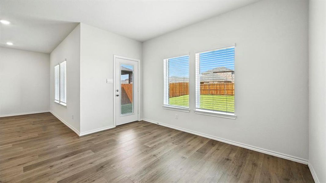 Spacious room featuring wood-finish flooring, white walls, and recessed lighting