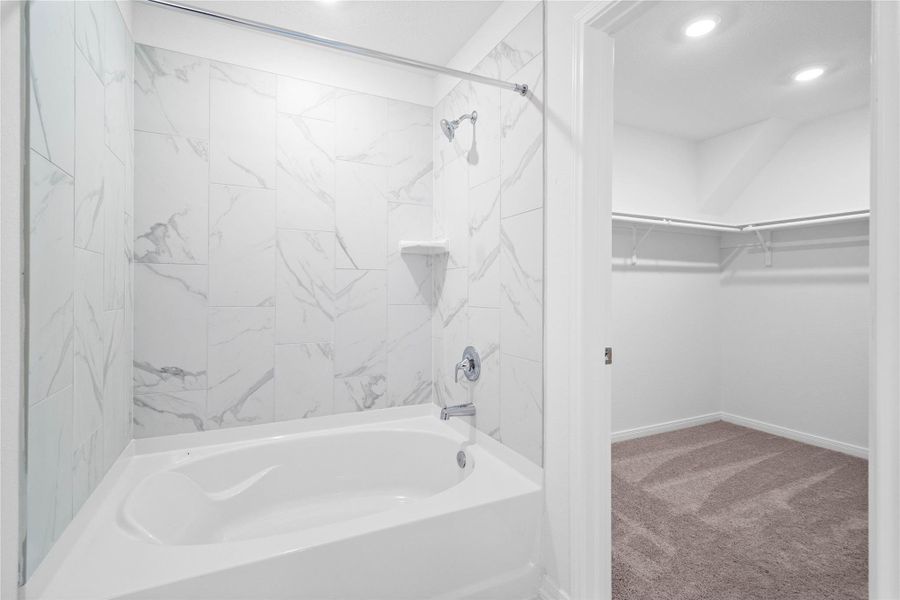 This alternate view of the primary bathroom showcases a large tub/shower combination with tile surround and the walk-in closet! This alternate view of the primary bathroom showcases a large tub/shower combination with tile surround and the walk-in closet!